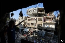 Palestinians inspect the rubble of a house after it was hit by an Israeli missile strike in Gaza City, July 10, 2014.