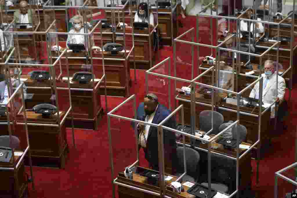 Rhode Island Democratic Representative Raymond Hull, low center, holds a microphone on the floor of the House Chamber separated by plastic protective barriers at the start of a legislative session,&nbsp; June 17, 2020, at the Statehouse in Providence.