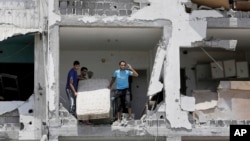 Mideast Israel PalestiniansPalestinians salvage what they can of their belongings from the rubble of their destroyed apartment in a building hit by an Israeli strike in Beit Lahiya, northern Gaza Strip, Aug. 4, 2014. 