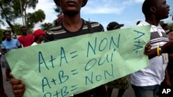 FILE - A protester holds a sign that reads in French "A+A=No. A+B=Yes. B+B=No" during an anti-gay demonstration in Port-au-Prince, Haiti.