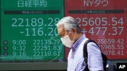  مردی از مقابل تابلوی الکترونیک بازار عرضه سهام در توکیو رد می شود. ۱۵ ژوئن ۲۰۲۰