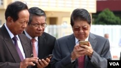 FILE PHOTO - Senior Cambodian government officers are using their smartphones while awaiting the return of Cambodian Prime Minister Hun Sen from France at Phnom Penh International Airport.