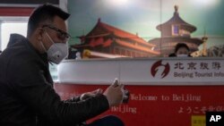 A traveler waits near a tourist information booth at the Capital International Airport terminal 3 in Beijing, March 12, 2020.