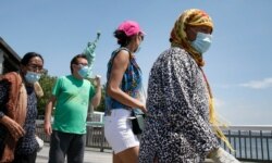 Visitors walk around Liberty Island on its first day of reopening since the start of the coronavirus pandemic, Monday, July 20, 2020, in New York. The Statue of Liberty remains closed.