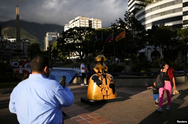 People walk past a sculpture by Venezuelan artist Antonio Azzato as part of the “Meninas Caracas Gallery” street exhibit which pays homage to Spanish artist Diego Velazquez’s “Las Meninas” in Caracas, Venezuela, January 10, 2024. (REUTERS/Gaby Oraa)