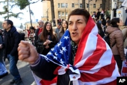 FILE - A protester shouts slogans during a rally against a law aimed at curbing the influence of "foreign agents," near the Georgian parliament building in Tbilisi, Georgia, on March 10, 2023.