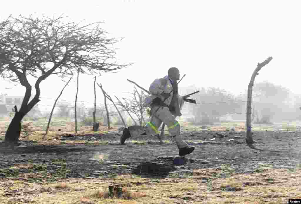 A miner runs as police shoot outside a South African mine in Rustenburg, August 16, 2012. 