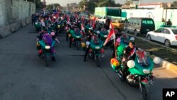 Iraqi security forces parade on motorcycles with national flags marking the one-year anniversary of the defeat of the Islamic State group in Iraq, in Tahrir Square, central Baghdad, Dec. 10, 2018.