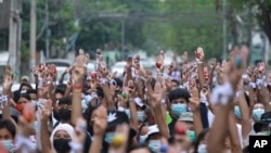 Pengunjuk rasa antikudeta mengangkat telur Paskah yang dihias bersama dengan simbol perlawanan tiga jari selama protes terhadap kudeta militer pada Minggu Paskah, 4 April 2021, di Yangon, Myanmar. (Foto: AP)