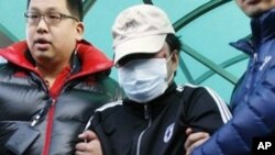 An unidentified Chinese captain, center, is led by South Korean police officers to the Incheon coast guard office from a hospital, where he received treatment following his arrest in Incheon, South Korea, on Monday, Dec. 12, 2011. A South Korean coast gua