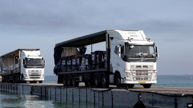 Truk-truk yang membawa bantuan kemanusaiaan dari Uni Emirat Arab dan Badan Pembangunan Internasional AS (USAID) melewati dermaga Trident sebelum tiba di pantai di Jalur Gaza, Jumat, 17 Mei 2024. (Foto: Staff Sgt. Malcolm Cohens-Ashley/U.S. Army via AP)