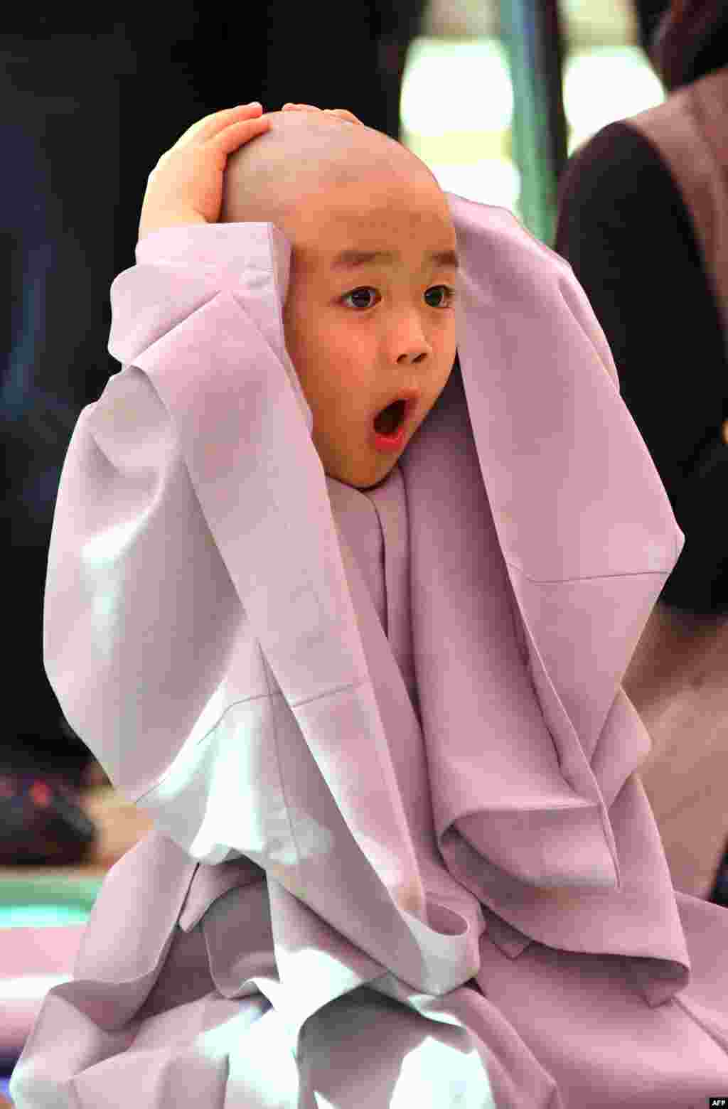 Seorang anak bereaksi setelah kepalanya dicukur botak oleh pendeta Budha pada acara pengenalan kehidupan biara di kuil Jogye, Seoul, Korea Selatan.