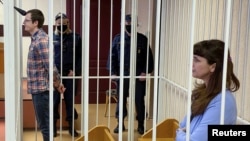 Jurnalis Belarus Katerina Borisevich dan dokter Artyom Sorokin berdiri di dalam sel sebelum sidang kasus mereka dimulai di Minsk, Belarus, pada 2 Maret 2021. (Foto: BelaPAN via Reuters)