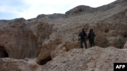 Two fighters from the Syrian Democratic Forces, the Kurdish-Arab alliance backed by the US fighting the Islamic State (IS) group, stand at the Tal Ajaja archeological site in Syria's northeastern Hassakeh province, Aug. 3, 2016.