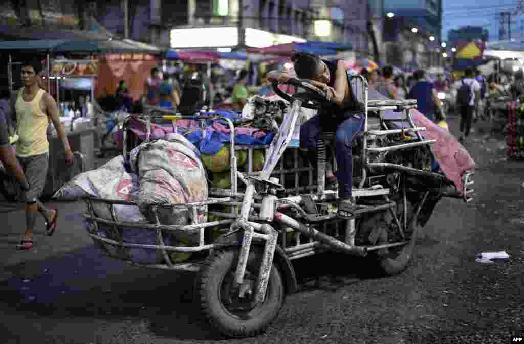 Seorang pekerja yang mengantar sayuran beristirahat di atas rickshaw-nya di Pasar Divisoria, Manila, Filipina.