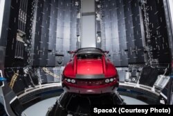 This Dec 6, 2017 photo made available by SpaceX shows a Tesla car next to the fairing of a Falcon Heavy rocket in Cape Canaveral, Fla. For the Heavy’s inaugural flight, the rocket will carry up Elon Musk’s roadster. In addition to SpaceX, Musk runs the el