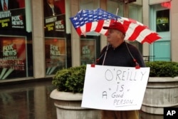 Douglas Esposit, of New York City, wears a Bill O'Reilly sign as he walks by the Fox television studios in New York, April 20, 2017. Despite the inglorious end to O'Reilly's two-decade Fox News Channel career, observers say his deep imprint on Fox and other cable news outlets and his influence on barbed political discourse are intact for the foreseeable future.