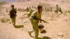 FILE - An Eritrean soldier carries his rifle and teapot as the Eritrean army begins to pull out from the frontline near Senafe, Feb. 17, 2001. 