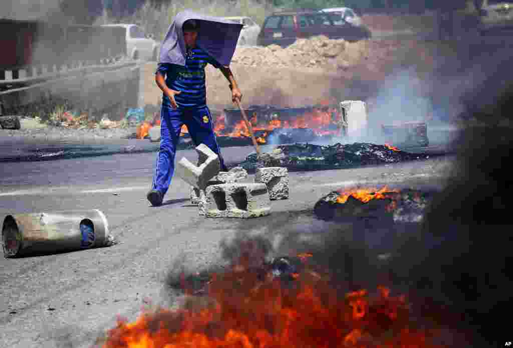 An Iraqi Kurd helps block a road during a demonstration against the fuel crisis in Irbil.