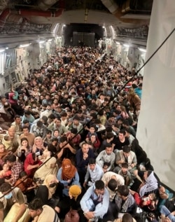 Afghan citizens pack inside a U.S. Air Force C-17 Globemaster III, as they are transported from Hamid Karzai International Airport in Afghanistan, Sunday, Aug. 15, 2021.