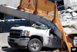A crushed pickup truck is shown under a new pedestrian bridge, Friday, March 16, 2018, after it collapsed Thursday onto a highway at a Miami-area college.