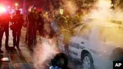 11月25日晚上，密蘇里州的弗格森一名警員上前查看遭一部冒煙的警車。有抗議者向警車投擲冒煙的裝置。