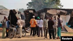 wakazi walokusanyika mbele ya majengo yaliyoharibiwa na shambulio la Jumapili huko Mpeketoni, Kenya, June 16, 2014. 