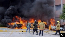 Firefighters try to extinguish burning vehicles in front of the state congress building after protesting teachers torched them in the state capital city of Chilpancingo, Mexico, Nov. 12, 2014. 