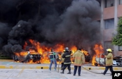 Firefighters try to extinguish burning vehicles in front of the state congress building after protesting teachers torched them in the state capital city of Chilpancingo, Mexico, Nov. 12, 2014.