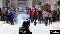 Riot officer fires teargas during clashes with supporters of Islamist group Ansar al-Sharia at Hai al Tadamon, Tunis, May 19, 2013.