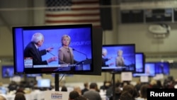 US Democratic presidential candidates Hillary Clinton and Bernie Sanders appear on television screens in the media work-room during the Democratic presidential candidates debate.