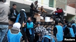 U.N. Relief and Works Agency (UNRWA) workers prepare aid parcels at the Palestinian refugee camp of Yarmouk, south of Damascus in this picture made available on February 26, 2014. World powers have passed a landmark Security Council resolution demanding a