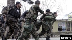 Pasukan keamanan Afghanistan menggendong rekannya yang terluka dalam baku tembak melawan kawanan bersenjata di Mazar-i-Sharif, Afghanistan, Senin (4/1).