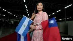 A Taiwanese citizen living in Managua holds Nicaragua's flag and Taiwan's flag as she waits for arrival of Tawain's President Tsai Ing-wen at the textile industrial park in Managua, Nicaragua Jan. 10, 2017. 