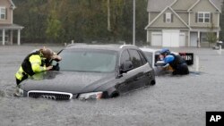 Members of the North Carolina Task Force urban search and rescue team check cars in a flooded neighborhood looking for residents who stayed behind as Florence continues to dump heavy rain in Fayetteville, N.C., Sunday, Sept. 16, 2018.