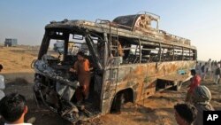 Warga berkerumun di sekitar rongsokan bus penumpang yang terbakar hangus setelah bertabrakan dengan kapal tanki, 50 kilometer di luar Karachi, Pakistan (11/1).