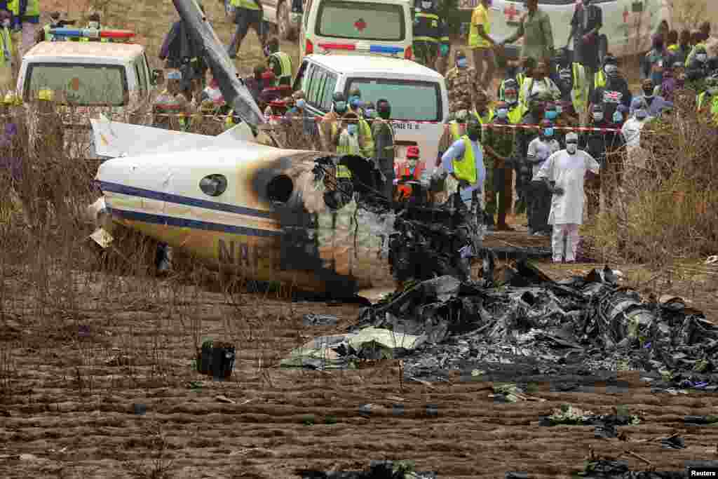 Rescuers and people gather near the debris of a Nigerian air force plane, which crashed while approaching the Abuja airport runway in Abuja.