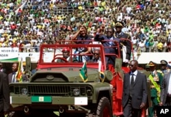 FILE - Zimbabwean President Robert Mugabe (C-R) and his wife Grace (C-L), greet the crowd as they arrive for his inauguration in Harare, Aug. 22, 2013.