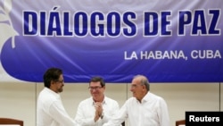 Colombia's FARC lead negotiator Ivan Marquez (L) and Colombia's lead government negotiator Humberto de la Calle (R) shake hands while Cuba's Foreign Minister Bruno Rodriguez looks on, after signing a final peace deal in Havana, Cuba, Aug. 24, 2016