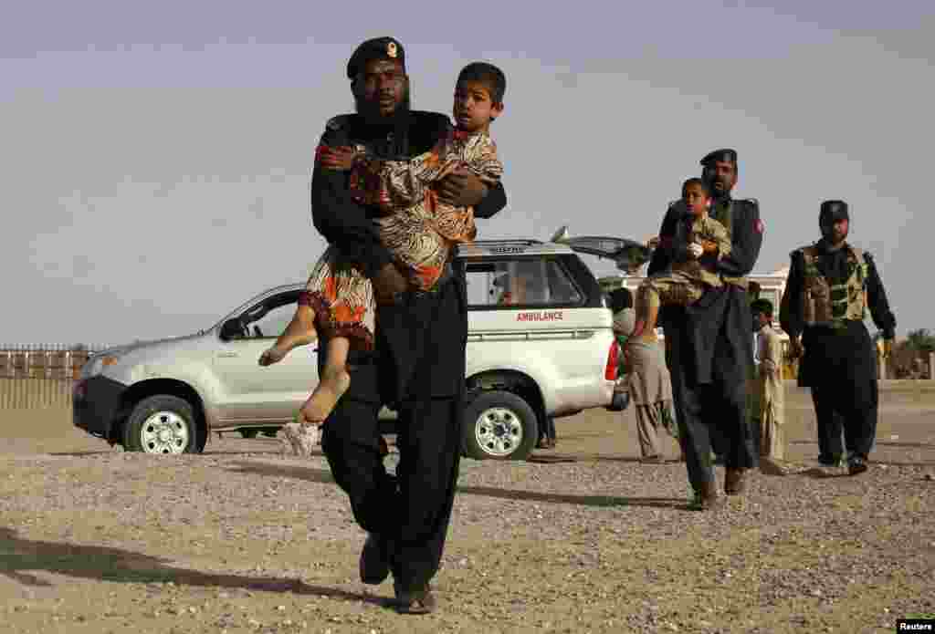 Paramilitary soldiers carry survivors of an earthquake to receive medical treatment following the quake in the town of Mashkeel, southwestern Pakistani province of Baluchistan, near the Iranian border. 