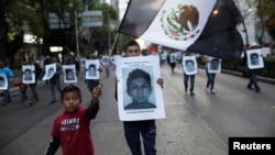 Demonstrators carry photos of 43 missing trainee teachers as a boy waves a Mexican flag, with its green and red parts replaced with black as a sign of mourning, during a march in support of the students in Mexico City, Dec. 6, 2014.