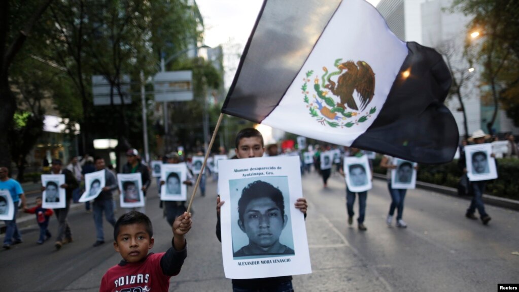 FILE - Demonstrators carry photos of the 43 missing trainee teachers as a boy waves a Mexican flag, with its green and red parts replaced with black as a sign of mourning, during a march in support of the students in Mexico City, Dec. 6, 2014.
