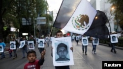 FILE - Demonstrators carry photos of the 43 missing trainee teachers as a boy waves a Mexican flag, with its green and red parts replaced with black as a sign of mourning, during a march in support of the students in Mexico City, Dec. 6, 2014.