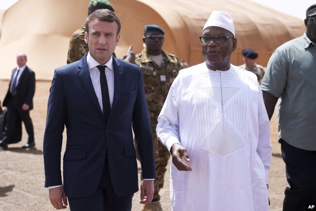FILE - French President Emmanuel Macron, left, talks to Mali's President Ibrahim Boubacar Keita as they meet French soldiers of Operation Barkhane, France's largest overseas military operation, in Northern Mali, May 19, 2017.
