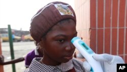 Un enseignant utilise un thermomètre pour tester la température des élèves à la recherche de signes du virus Ebola à l'école maternelle Aiyetoro African Church, Lagos, au Nigeria, le 8 octobre 2014. 