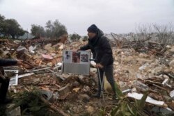 Seorang pria Palestina membawa foto keluarga di reruntuhan sebuah rumah yang dihancurkan oleh pemerintah kota Yerusalem, di Sheikh Jarrah, Yerusalem timur Rabu, 19 Januari 2022.