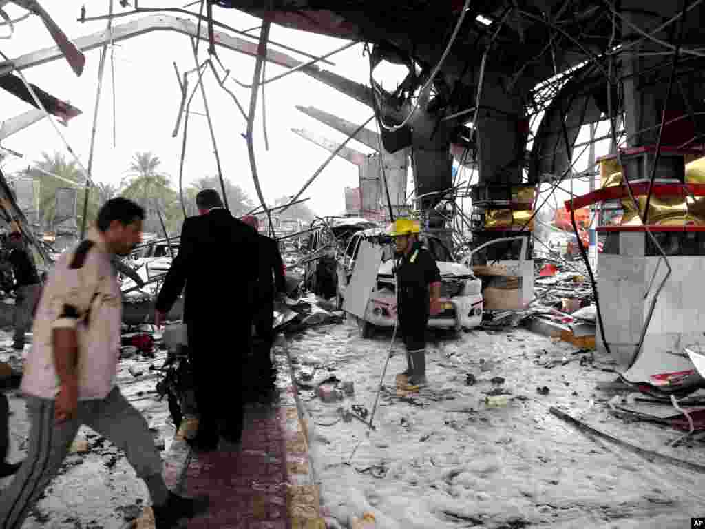 شهروندان غيرنظامی و نيروهای انتظامی محل انفجار سهمگين در حله (۹۰&nbsp;کيلومتری جنوب بغداد) را بررسی می کنند.&nbsp;- ۱۸ اسفندماه