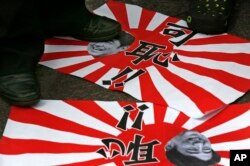 香港的反日示威者践踏日本军旗和安倍首相的照片