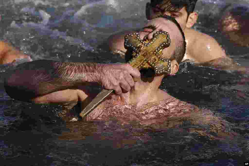 Nicolaos Solis from Greece kisses the wooden cross which was thrown into the waters by Ecumenical Patriarch Bartholomew I, during the Epiphany ceremony to bless the waters at the Golden Horn in Istanbul, Turkey, Jan. 6, 2018.