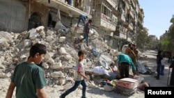 People remove belongings from a damaged site after an air strike Sunday in the rebel-held besieged Qaterji neighborhood of Aleppo, Syria, Oct. 17, 2016. 